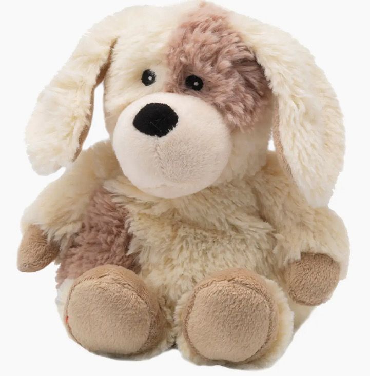 A plush toy dog with floppy ears and a patchy brown and cream fur pattern is sitting upright.