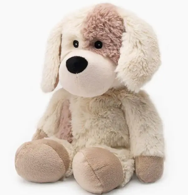 A plush toy dog with beige and white fur, brown spots, large floppy ears, and a black nose sits upright.
