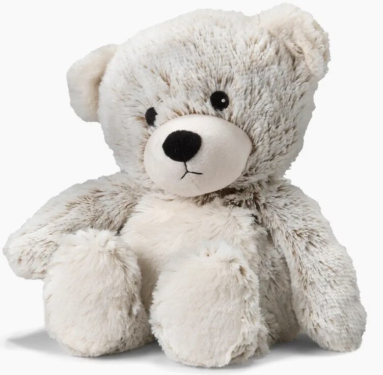 A fluffy white teddy bear with black eyes and nose sits upright on a plain background.