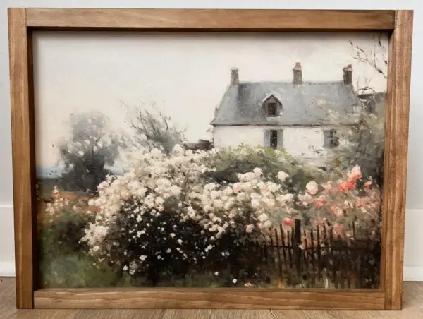 Framed painting titled "Landscape | Summer Home Decor," featuring a cottage with a white roof, nestled among blooming bushes and trees, set against a cloudy sky.