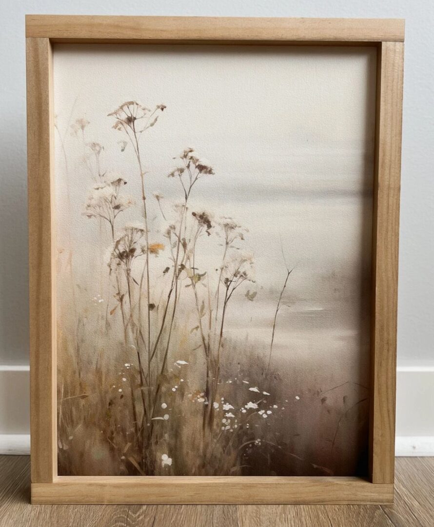 A vintage print featuring wildflowers on a misty landscape with muted earth tones, displayed on a wooden floor, perfect for fall home decor.