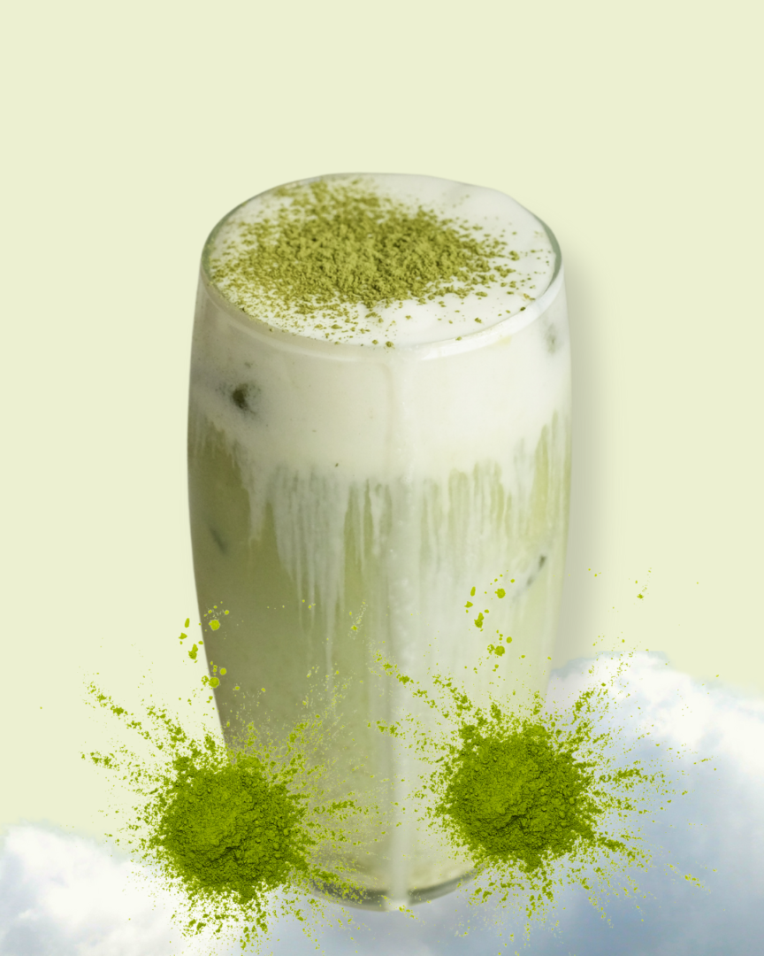 A tall Iced Matcha with foam and a sprinkle of matcha powder on top sits beside two piles of matcha powder.