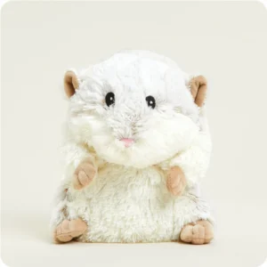 The Hamster Warmies Junior, a plush toy with white and light brown fur, sits upright against a plain, light background.
